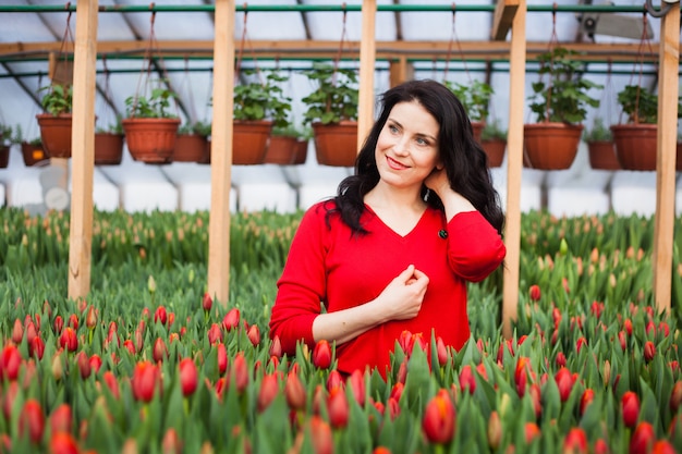 Fille avec des tulipes cultivées dans une serre.