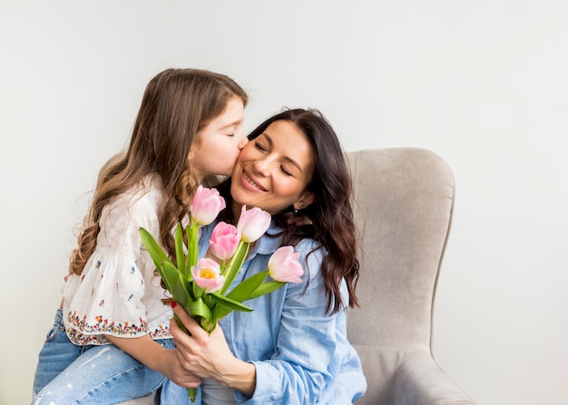 Fille avec des tulipes embrassant mère sur la joue