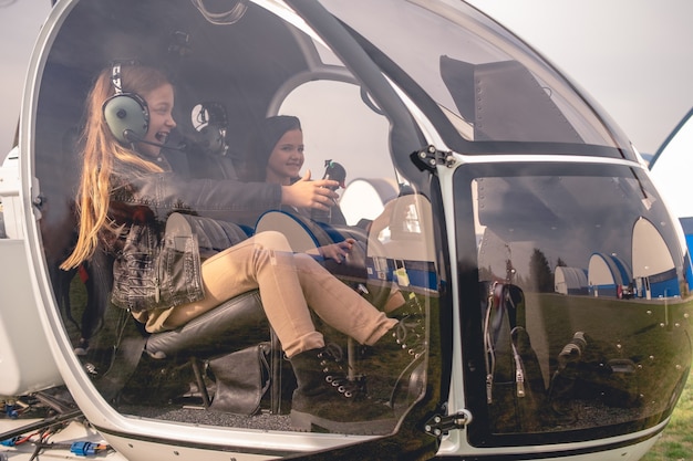 Photo fille tween excitée dans un casque d'aviateur assis dans un cockpit d'hélicoptère