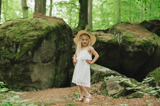 Fille ukrainienne de 7 ans aux cheveux blancs comme un ange marchant dans les bois sur les rochers