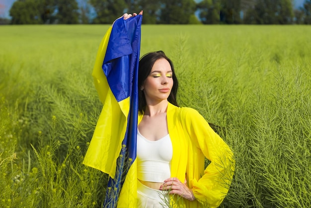 Fille ukrainienne avec un drapeau bleu-jaune dans ses mains sur le fond du champ
