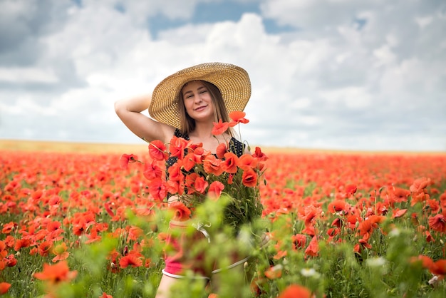 Fille ukrainienne en tenue de sport tenant un bouquet de coquelicots dans le champ, l'heure d'été