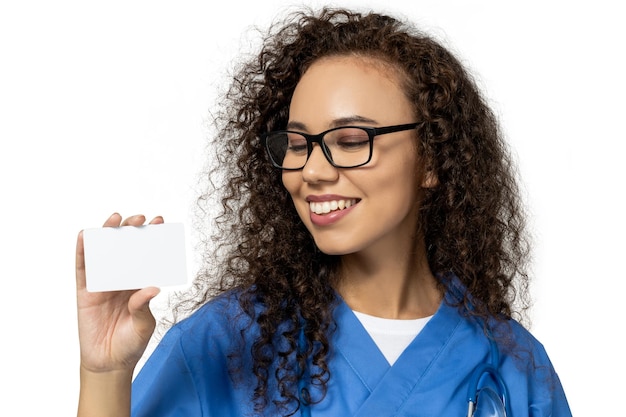 Une fille en uniforme d'infirmière bleu avec une feuille de papier vierge isolée sur fond blanc