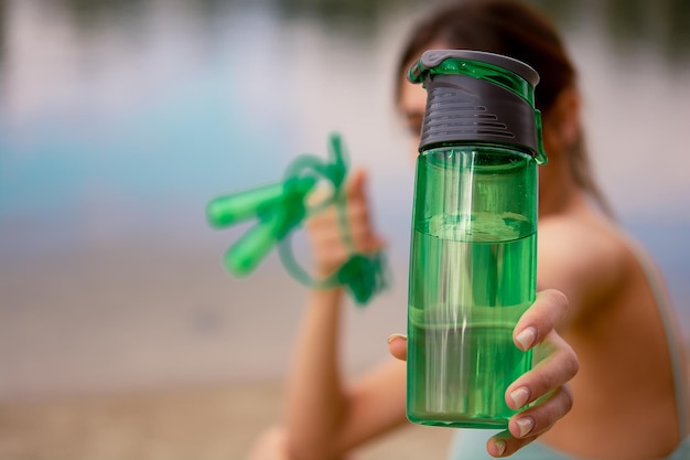 une fille en uniforme de sport tient une corde à sauter dans ses mains, vêtue d'un haut de survêtement vert