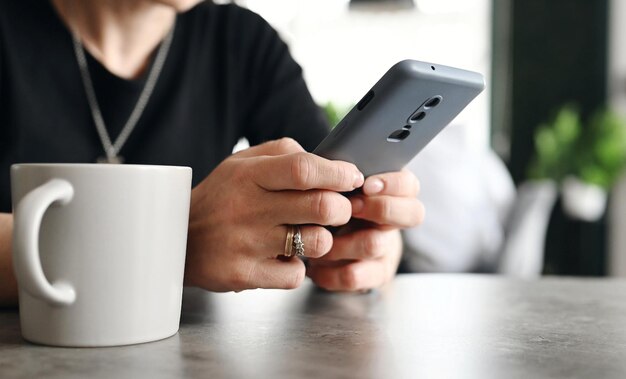 Une fille utilisant un smartphone pour un travail sur Internet et des médias sociaux dans le café