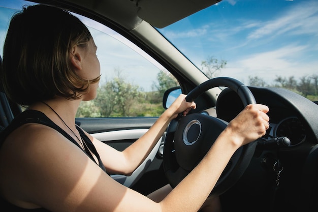 La fille va derrière le volant d'une voiture