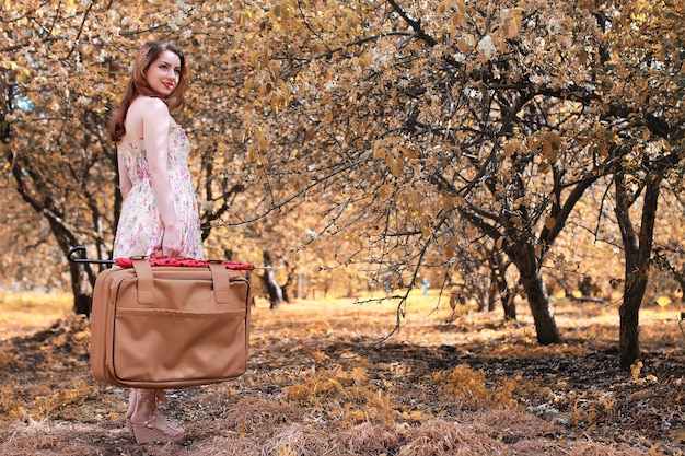 fille avec valise en cuir pour voyager dans le parc en automne en promenade