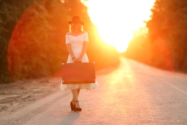 Photo fille avec une valise faisant de l'auto-stop