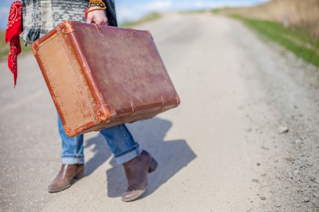 Fille avec une valise sur la route