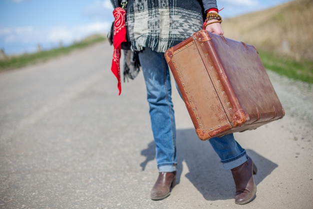 Fille avec une valise sur la route