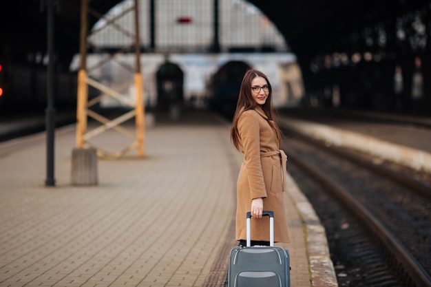 Fille avec une valise voyage. Vous cherchez un bus à la gare.