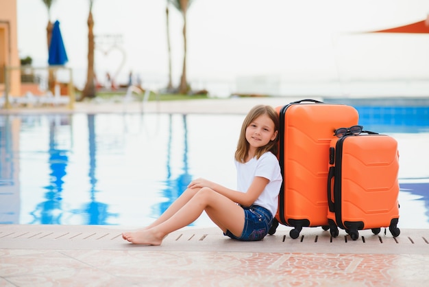 Fille avec des valises au bord de la piscine dans un hôtel de luxe