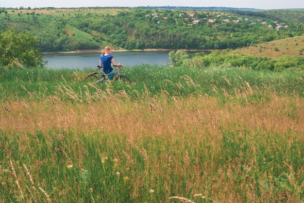 Fille avec un vélo au bord de la rivière. Une fille est assise sur un vélo près d'une tente sur le vélo. Le t de voyage et de liberté.