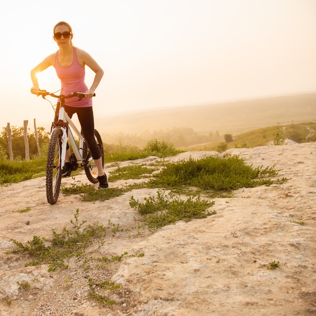 Fille en vélo de montagne sur le sentier sur un beau lever de soleil