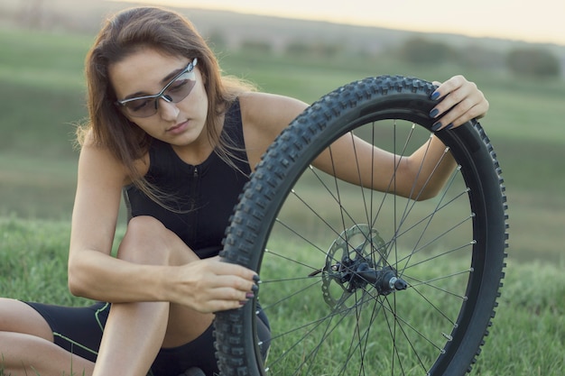 Fille sur un vélo de montagne sur tout-terrain, beau portrait d'un cycliste au coucher du soleil