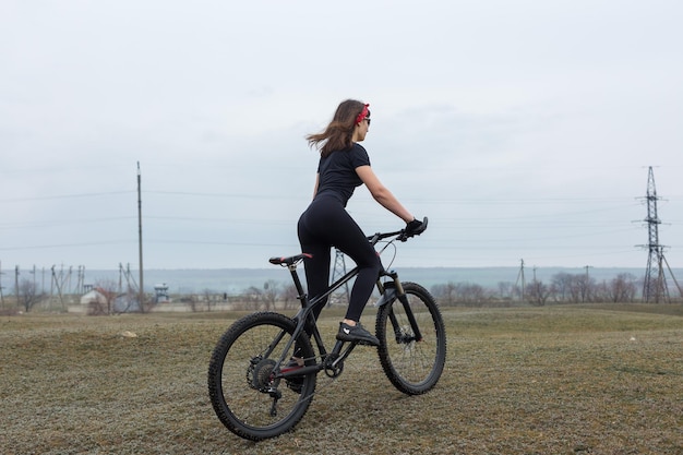 Fille sur un vélo de montagne sur tout-terrain beau portrait d'un cycliste par temps de pluie Fille de remise en forme monte un vélo de montagne moderne en fibre de carbone en vêtements de sport Portrait en gros plan d'une fille en bandana rouge