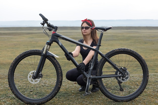 Fille sur un vélo de montagne sur tout-terrain beau portrait d'un cycliste par temps de pluie