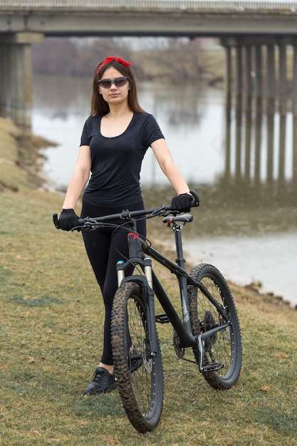 Fille sur un vélo de montagne sur tout-terrain beau portrait d'un cycliste par temps de pluie