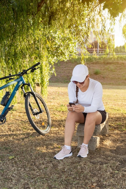 Une fille vérifie les médias sociaux sur son téléphone portable après avoir fait de l'exercice sur son vélo