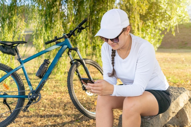 Une fille vérifie les médias sociaux sur son téléphone portable après avoir fait de l'exercice sur son vélo