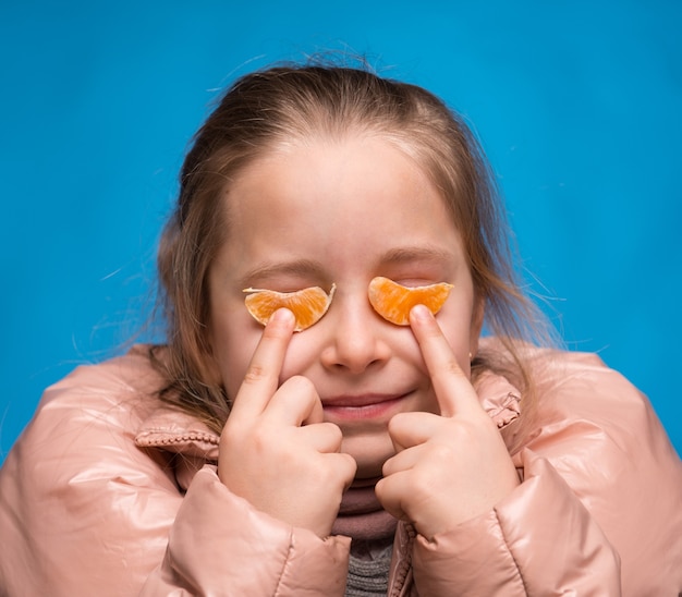 Fille avec des verres de mandarine sur fond bleu