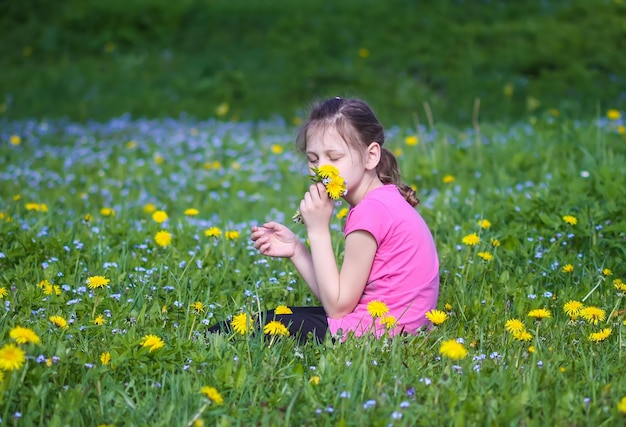 Une fille sur la verte prairie printanière avec beaucoup de fleurs sauvages au soleil. Enfant explorant la nature.