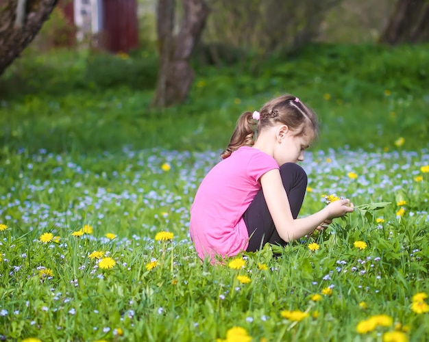 Une fille sur la verte prairie printanière avec beaucoup de fleurs sauvages au soleil. Enfant explorant la nature.