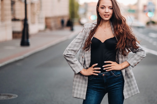 Une fille en veste et cheveux longs se promène dans la vieille ville.Une belle fille sourit.Fille sur la route