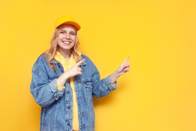 Fille en veste en jean et casquette montre avec sa main sur l'espace de copie