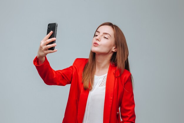 Fille en veste rouge prend un selfie au téléphone