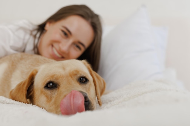 Fille en vêtements blancs avec chien labrador jouant à la maison