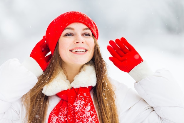 Fille en vêtements d'hiver, main dans la main dans des gants près de chapeau rouge