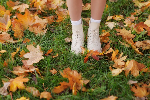 Fille en vêtements jaunes dans le parc d'automne se réjouit en automne tenant des feuilles jaunes dans ses mains au chaud