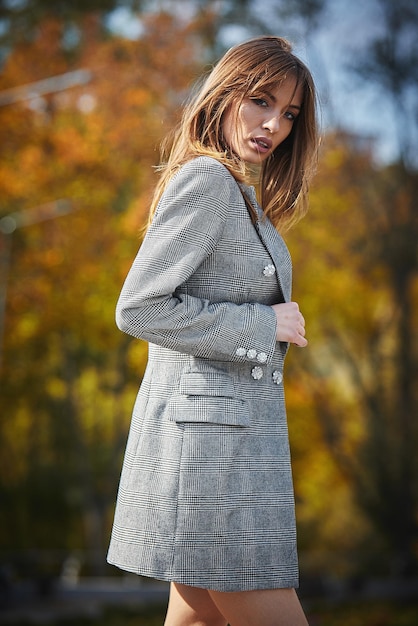 Une fille en vêtements de marque marche dans un parc en automne