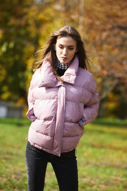 Une fille en vêtements de marque marche dans un parc en automne