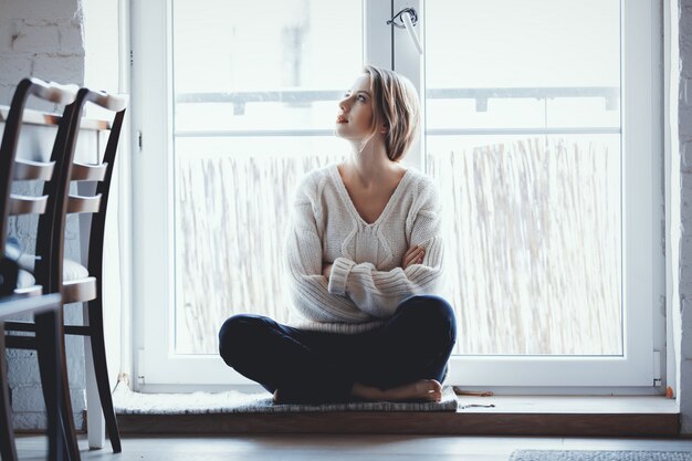 Une fille vêtue d'un pull est assise au seuil