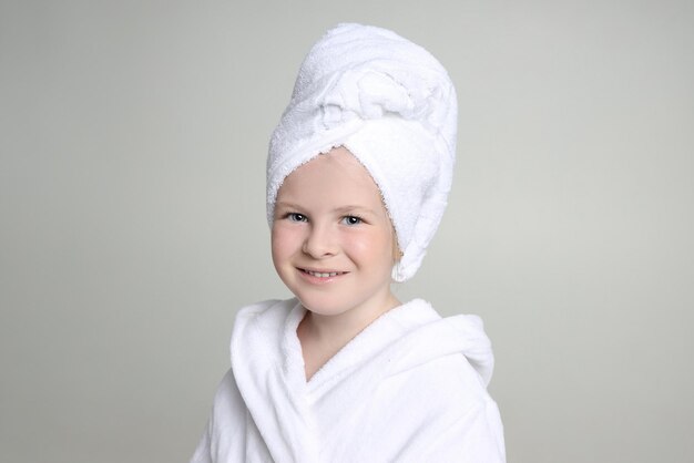 Fille vêtue d'une robe blanche et d'une serviette sur la tête après une douche et se lavant les cheveux. Cosmétiques et soins de la peau pour enfants, Soins spa. Cheveux propres et beaux. Russie Sverdlovsk, le 20 août 2019