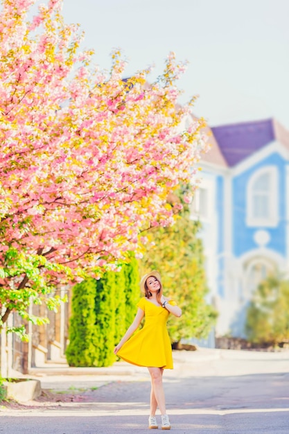 Une fille vêtue d'une robe et d'un chapeau se promène dans la rue de la ville par une belle journée de printemps