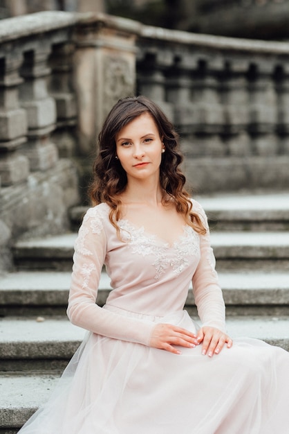 Une fille vêtue d'une robe rose clair dans la perspective d'un château de pierre polonais médiéval