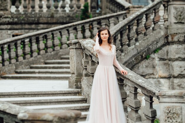 Une fille vêtue d'une robe rose clair dans la perspective d'un château de pierre polonais médiéval