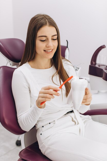 La fille en visite chez le dentiste montre comment elle se brosse les dents