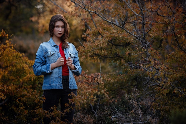 Fille voyage dans la forêt des montagnes Une fille dans une veste en jean et un t-shirt rouge Montagnes en automne Voyage Style de vie et concept de survie