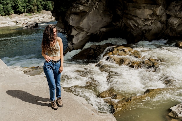 Fille voyageant dans les montagnes des Karpates et se sentant libre. Cascade dans la rivière de montagne.