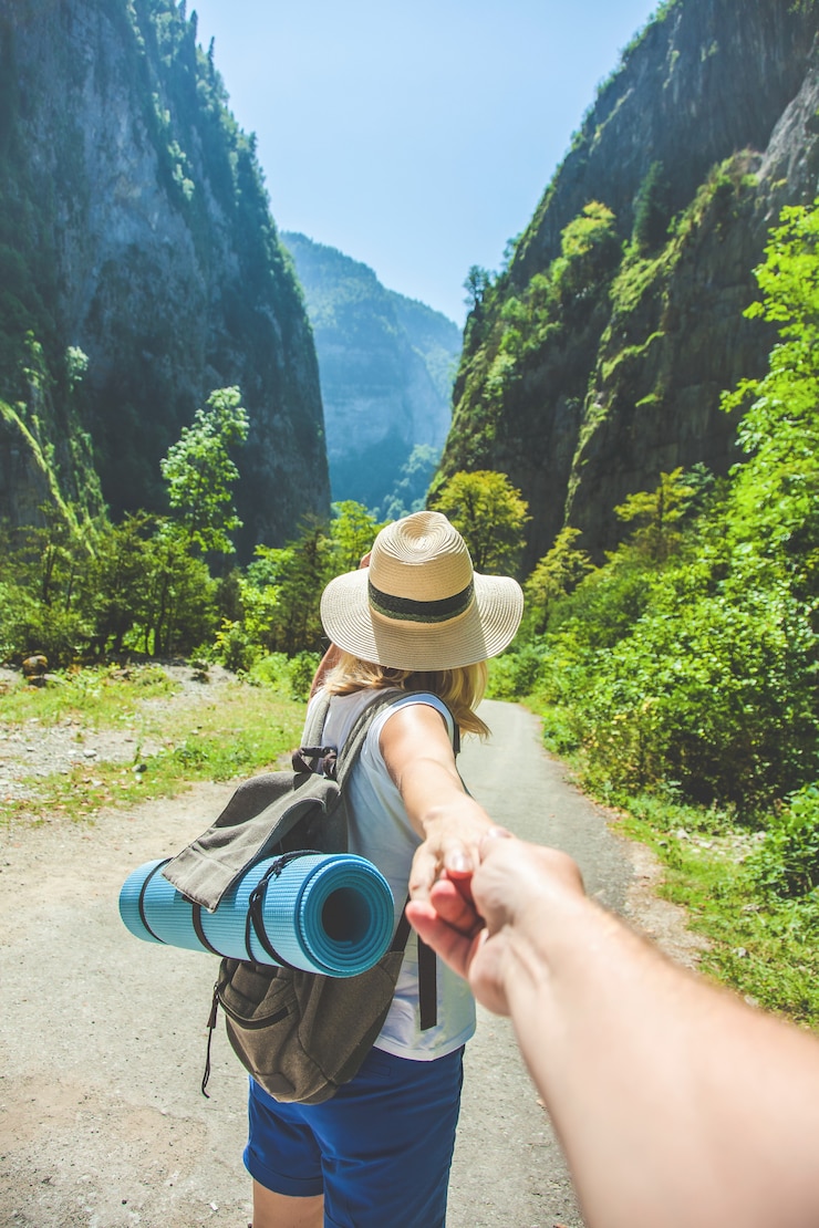 Photo fille voyageur dans un chapeau mène la main d'un gars sur le fond des voyageurs de la montagne