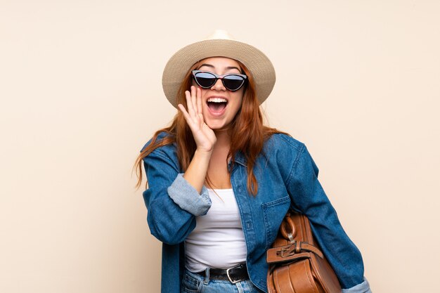 Fille de voyageur rousse avec valise criant avec la bouche grande ouverte