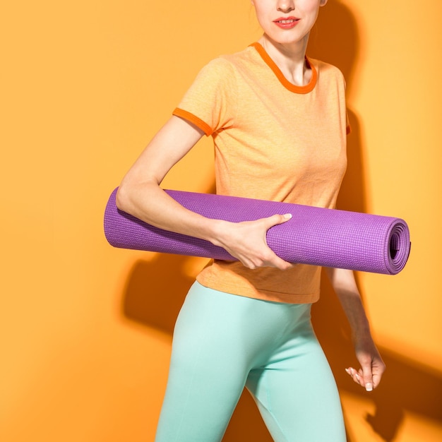 Fille de yoga sportive avec tapis de yoga isolé sur fond orange jaune