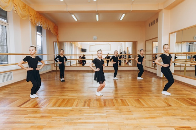 Des filles de 8 ans en costume noir font une chorégraphie dans une classe de ballet.