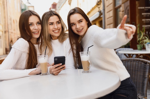 filles à l'aide d'un smartphone à une table de cafétéria