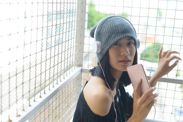 Les filles asiatiques écoutent la musique du casque et de son smartphone.