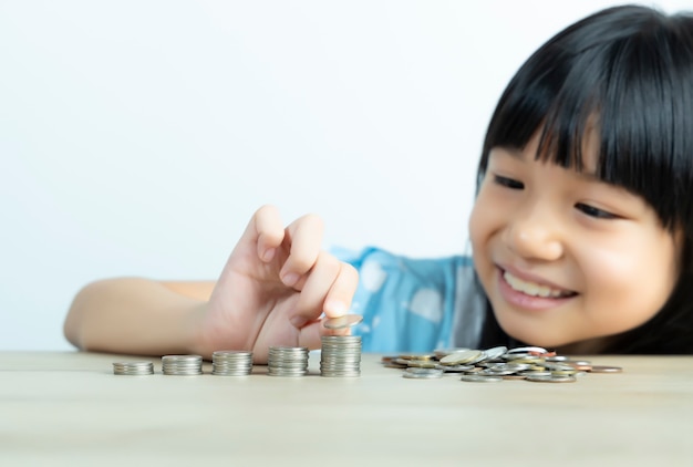 Les filles asiatiques sont heureuses d'organiser des pièces et de compter les pièces pour économiser de l'argent avec le mur blanc.